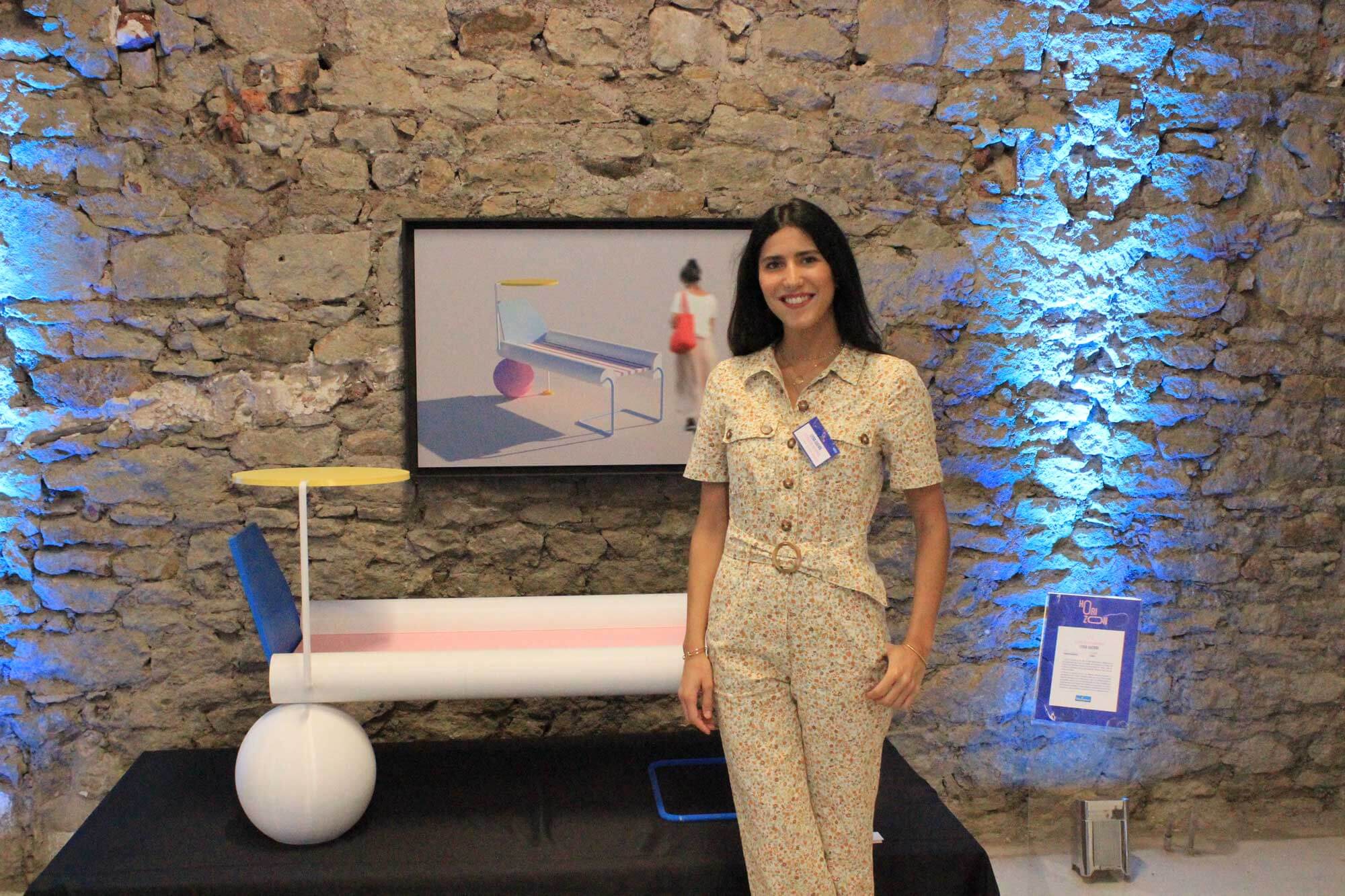 Lauréat du concours Horizon 3D, une femme posant à côté d'un banc moderne imprimé en 3D, mur en pierre avec éclairage bleu en arrière-plan