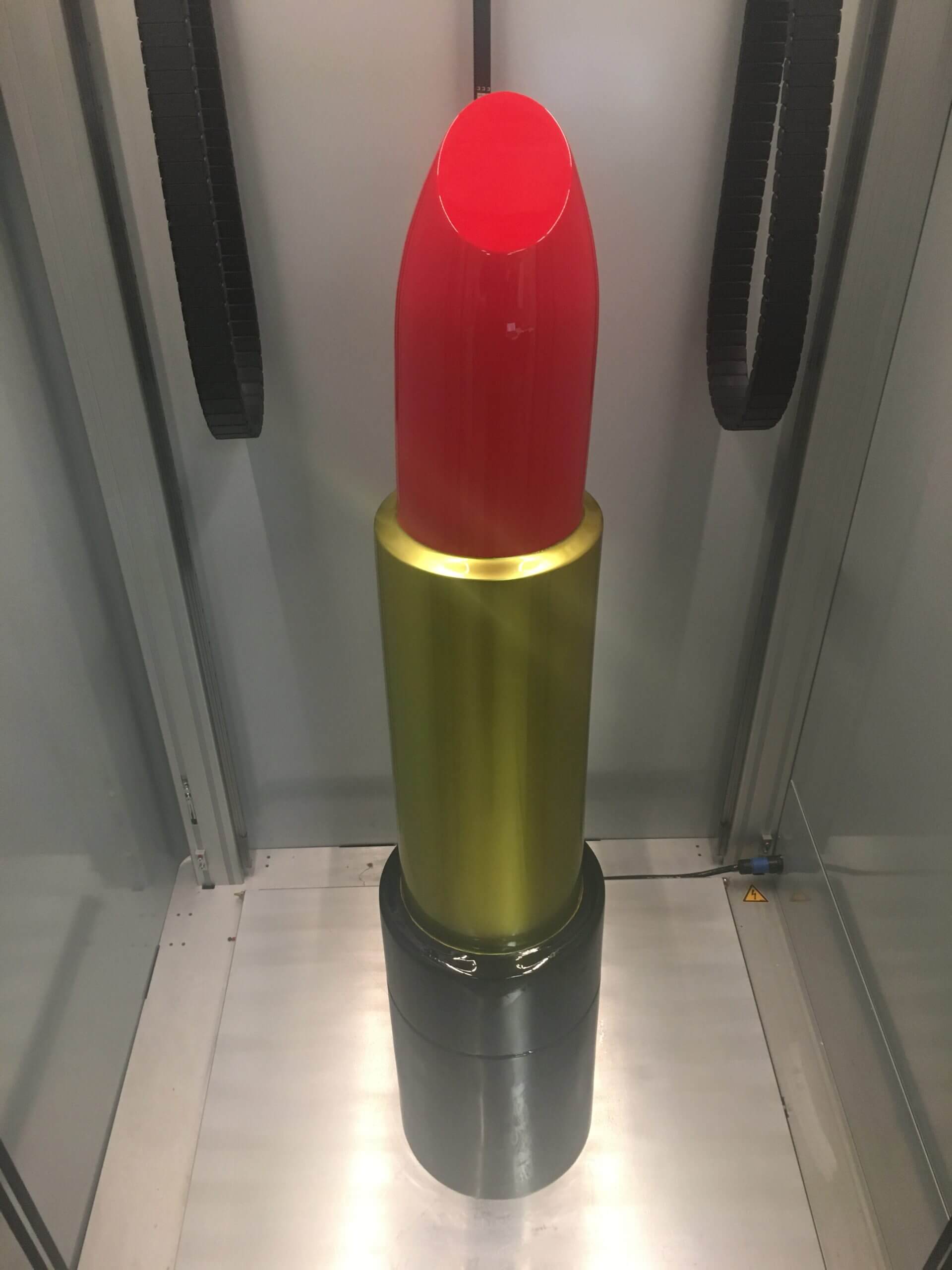 Publicité sur lieu de vente (PLV) en forme de rouge à lèvres imprimée en 3D, avec un bâton rouge vif et un boîtier doré et noir