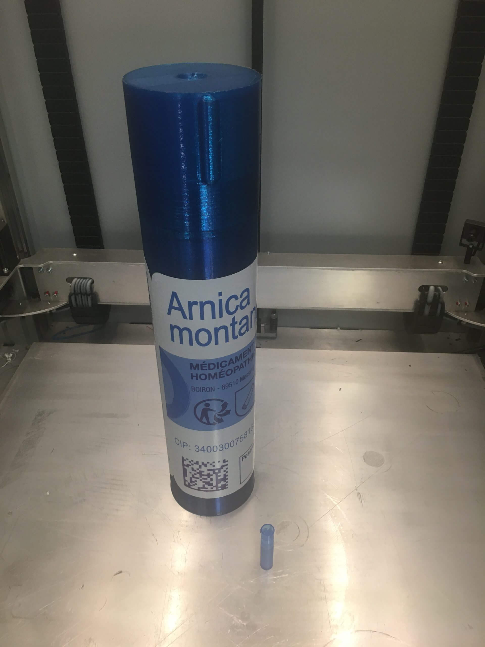Tube homéopathique bleu imprimé en 3D grand format avec bouchon transparent, présenté sur une surface métallique