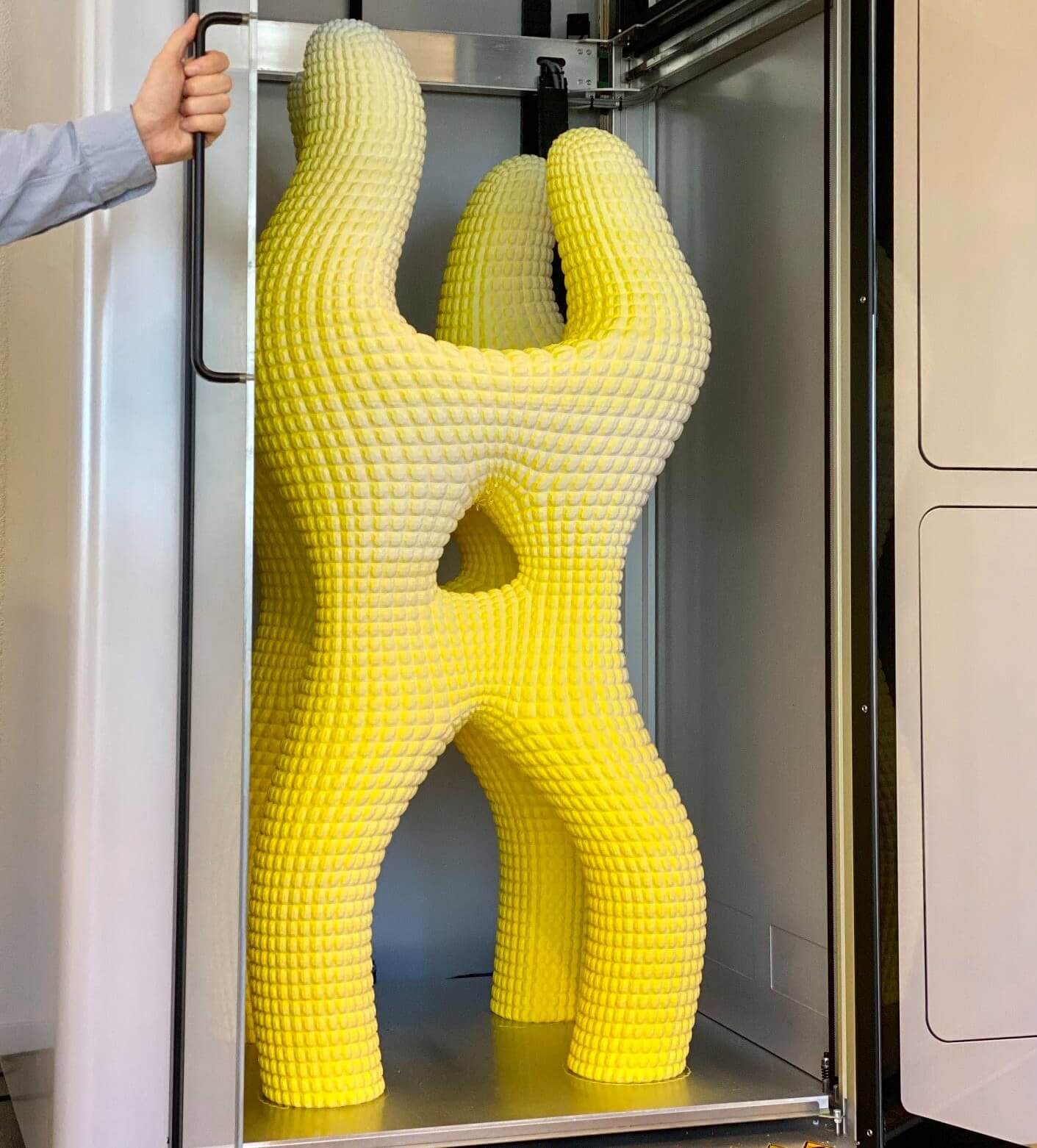 Sculpture jaune imprimée en 3D grand format, exposée dans une imprimante 3D professionnelle.